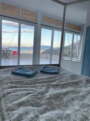 1 cama con 2 almohadas azules en una habitación con ventanas en Villa kaplumba, en Dalyan