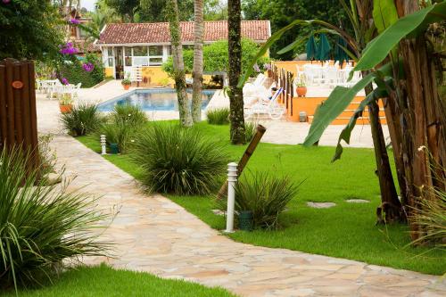 a garden with a swimming pool and a resort at Hotel Ilhasol in Ilhabela