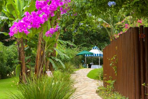 a garden with pink flowers and a fence and a gazebo at Hotel Ilhasol in Ilhabela