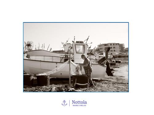 a man standing next to a boat on the beach at Nottola B&B in Ladispoli