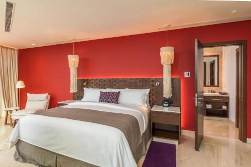 a bedroom with a large bed and a red wall at Camino Real Mérida in Mérida