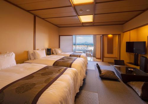 a hotel room with three beds and a television at Biwako Ryokusuitei in Otsu