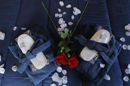 two pairs of shoes with a red rose on a bed at B&B Bellavista Exclusive in zona centrale con piscina riscaldata e Jacuzzi vista lago LA COLAZIONE viene servita in una pasticceria rinomata ed esclusiva esterna alla struttura in Desenzano del Garda