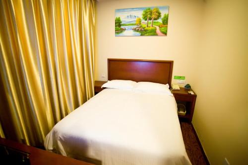 a bedroom with a white bed with a wooden headboard at GreenTree Inn Shanghai Meilan Lake Hutai Road Express Hotel in Baoshan