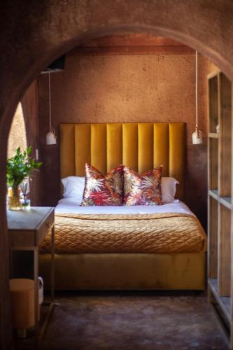 a bedroom with a bed with a yellow headboard and pillows at Le Héritage in Klein-Drakenstein