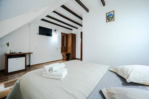 a white bedroom with a large bed with towels on it at Pension Valeria in Voronet