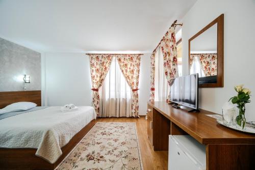 a bedroom with a bed and a mirror and a tv at Pension Valeria in Voronet