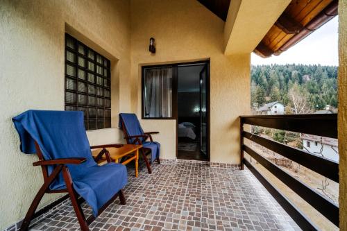 a porch with two blue chairs and a table at Pension Valeria in Voronet
