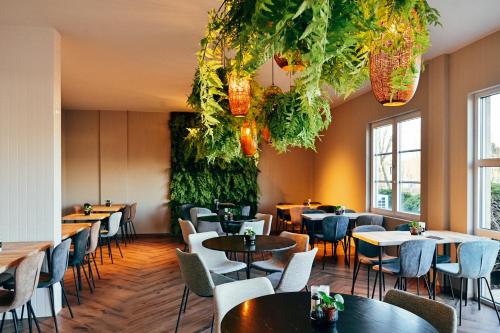 a restaurant with tables and chairs and plants at Hotel Ter Elst in Edegem