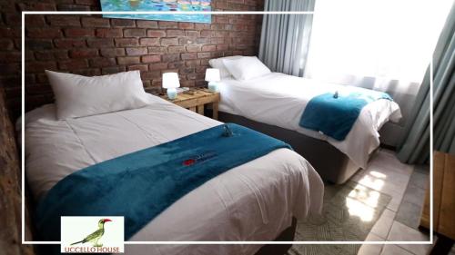 ein Hotelzimmer mit 2 Betten mit einem Vogel auf der Bettwäsche in der Unterkunft Uccellohouse in Marloth Park