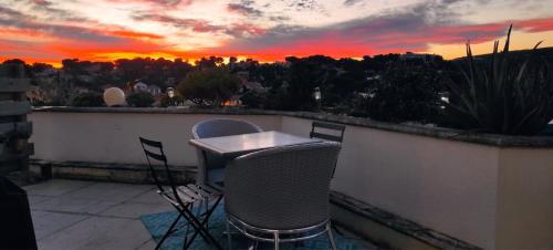 a table and chairs on a balcony with a sunset at grand studio terrasse de standing, pleine vue village et proche mer in Carry-le-Rouet
