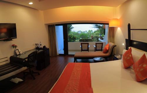 a hotel room with a bed and a desk and a television at Gateway Varkala in Varkala