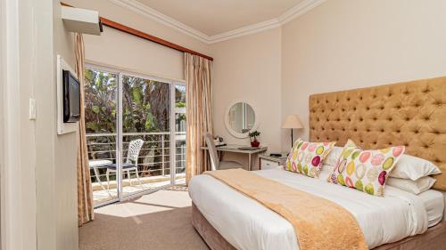 um quarto com uma cama grande e uma varanda em The Sir David Boutique Guest House em Bloubergstrand