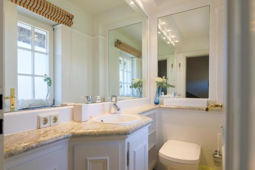 Un baño con lavabo, inodoro y espejo. en Haus Brönsheide, en Wenningstedt