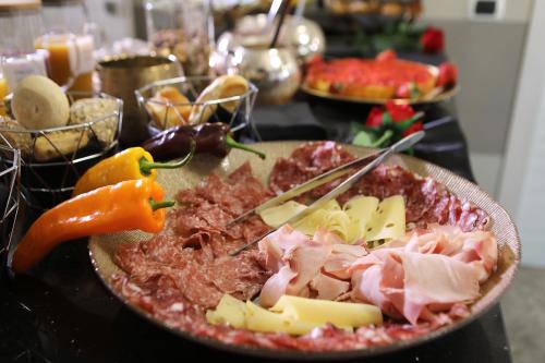 a plate of food with meat and cheese on a table at B&B Bellavista Exclusive in zona centrale con piscina riscaldata e Jacuzzi vista lago LA COLAZIONE viene servita in una pasticceria rinomata ed esclusiva esterna alla struttura in Desenzano del Garda
