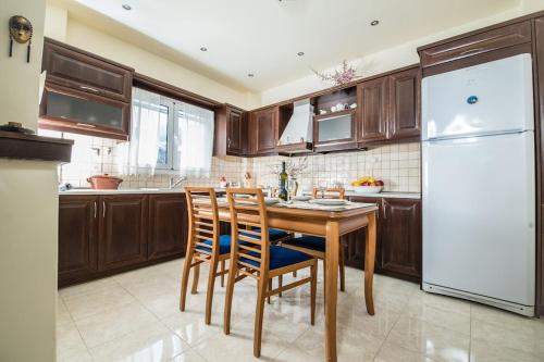a kitchen with a wooden table and a white refrigerator at Kreta House in Pómbia
