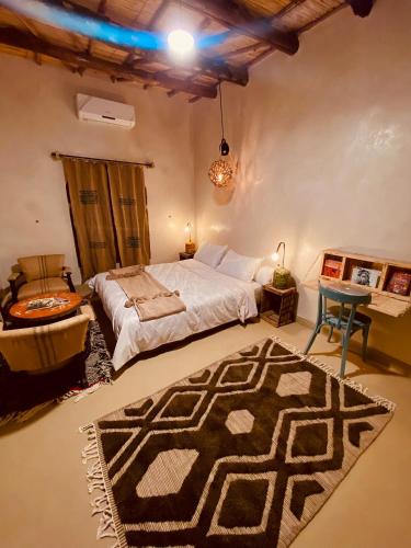 a bedroom with a bed and a rug on the floor at taman'art space in Aït Ben Haddou