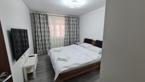 a bedroom with a white bed and a window at Focalize Apartament in Buzău