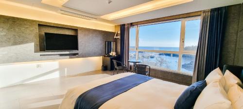 a bedroom with a large bed and a large window at Elren Hotel Jeju in Seogwipo