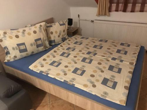 a bed with a comforter and pillows on it at Famvarga Apartmanház in Balatonfenyves