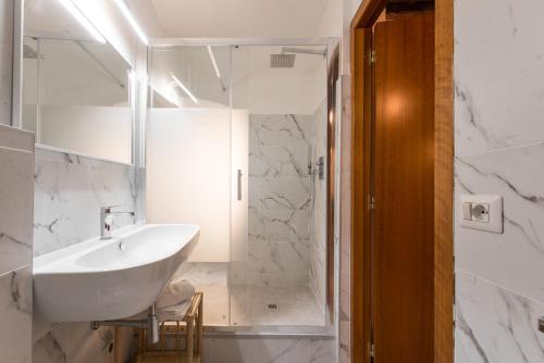 a white bathroom with a sink and a shower at Bernini Collection in Rome