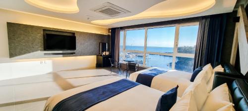 a hotel room with two beds and a large window at Elren Hotel Jeju in Seogwipo