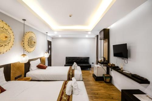 um quarto de hotel com duas camas e uma televisão de ecrã plano em Paraiso Hotel Chiangmai em Chiang Mai