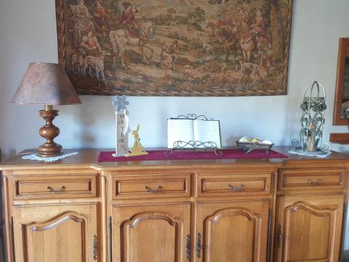 a wooden cabinet with a lamp and a painting on the wall at Le Wineck in Dambach