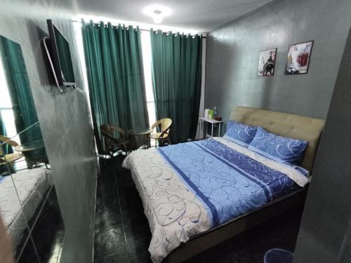 1 dormitorio con 1 cama con sábanas azules y cortinas verdes en Hotel Oasis, en Batang Kali