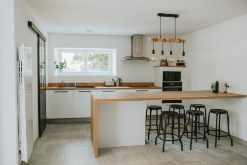 une cuisine avec des placards blancs et un comptoir avec des tabourets de bar dans l'établissement Maison de campagne avec salle de jeux 6 personnes, à Cuq