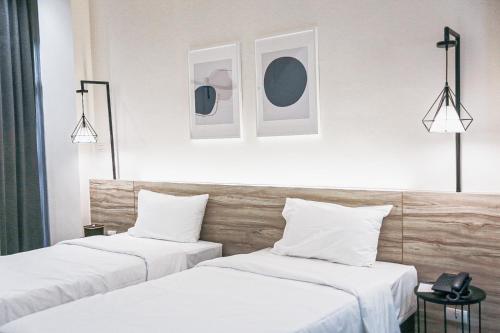 two beds in a hotel room with white walls at HOMITEL Bangkok in Bangkok