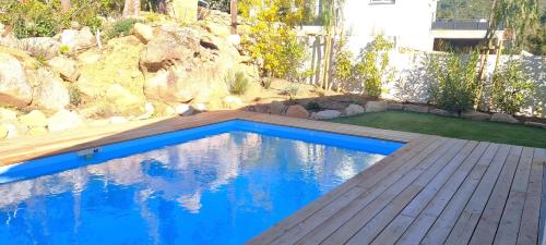 a swimming pool with a wooden deck and blue water at Villa Leku Lucia 8 pers piscine chauffée 15 min plage en voiture in Sainte-Lucie de Porto-Vecchio