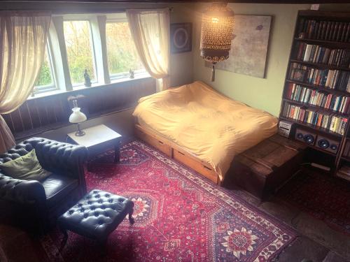 um quarto com uma cama, uma cadeira e uma estante de livros em Nutclough Cottage - Log Fire and Valley View - Sleeps 2 em Hebden Bridge