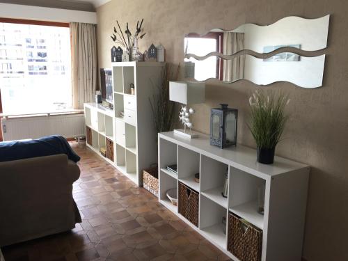 a living room with white shelves and a mirror at Wembley in Middelkerke