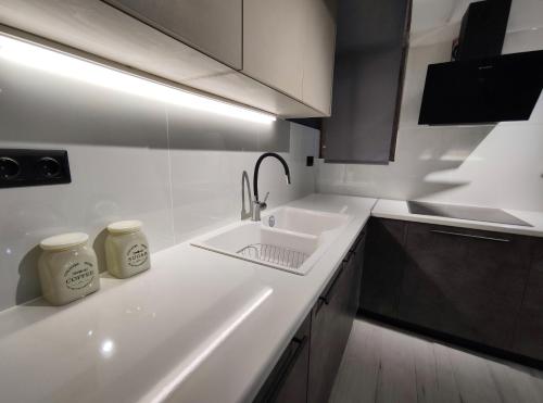 eine weiße Küche mit einem Waschbecken und einer Arbeitsplatte in der Unterkunft Beautifull And Airy Appartment Corfu Town in Kanoni