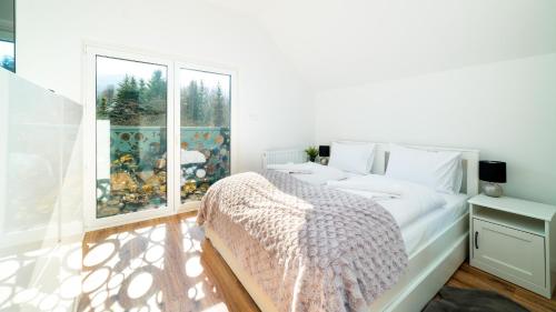 a white bedroom with a bed and a window at Domki Sun & Snow Sikorskiego II in Karpacz