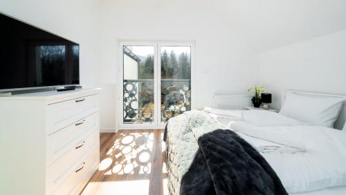 a white bedroom with a couch and a tv at Domki Sikorskiego II, Sun & Snow in Karpacz