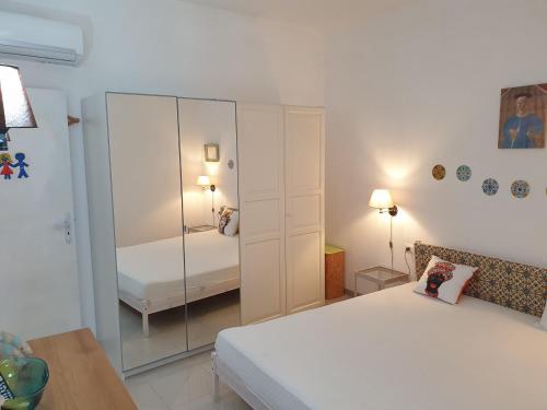 Schlafzimmer mit einem weißen Bett und einem Spiegel in der Unterkunft Casa Vacanza Giovanna nr 52 contrada Mezzacampa località Caporasocolmo Messina in Messina