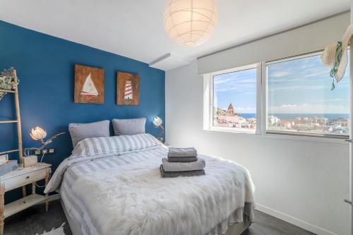 a bedroom with a large bed with blue walls and windows at Casita Kunterbunt in Alicante