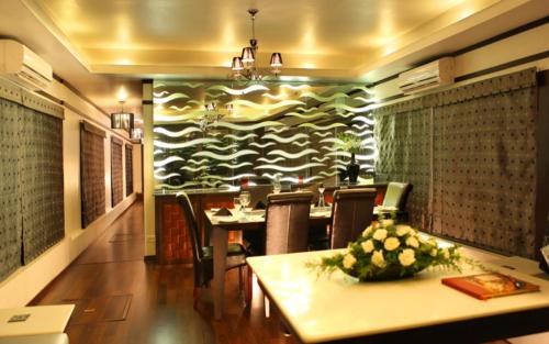 a dining room with a table and chairs and a wall at Sreekrishna Houseboat in Kumarakom