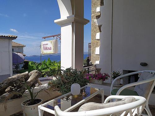 un balcón con una silla, una mesa y algunas plantas en Pension Filitsa, en Pylos