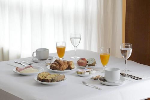 Hotel Paraíso Del Marisco في او غروف: طاولة بيضاء مع طعام وكؤوس من النبيذ