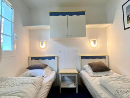 Cette chambre comprend 2 lits, une armoire et une table. dans l'établissement REF 057 - Appartement pour quatre personnes avec terrasse secteur port Crouesty ARZON, à Arzon