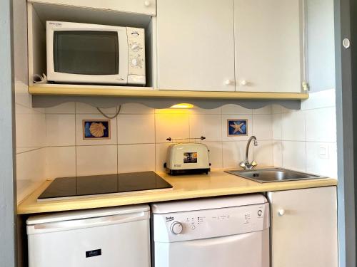 une petite cuisine avec un micro-ondes et un évier dans l'établissement REF 057 - Appartement pour quatre personnes avec terrasse secteur port Crouesty ARZON, à Arzon