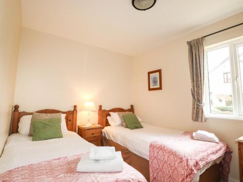 two twin beds in a room with a window at Tilly Mint Cottage in Penrith