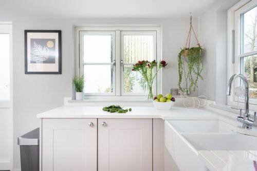 a white kitchen with white cabinets and a sink at Beach Cottage and The Lobster Pot in St. Agnes