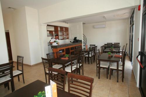 a restaurant with tables and chairs and a woman in a kitchen at New York Plaza Hotel Apartments in Paphos City