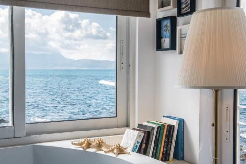 a table with a lamp and a window with a view of the ocean at Dream House Efi in Ravdhoúkha