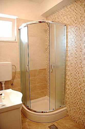 a shower with a glass door in a bathroom at House Zdenka in Tribunj