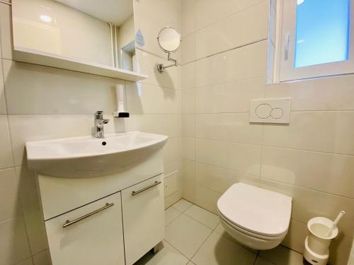 a white bathroom with a sink and a toilet at Kunstelj Pension in Radovljica